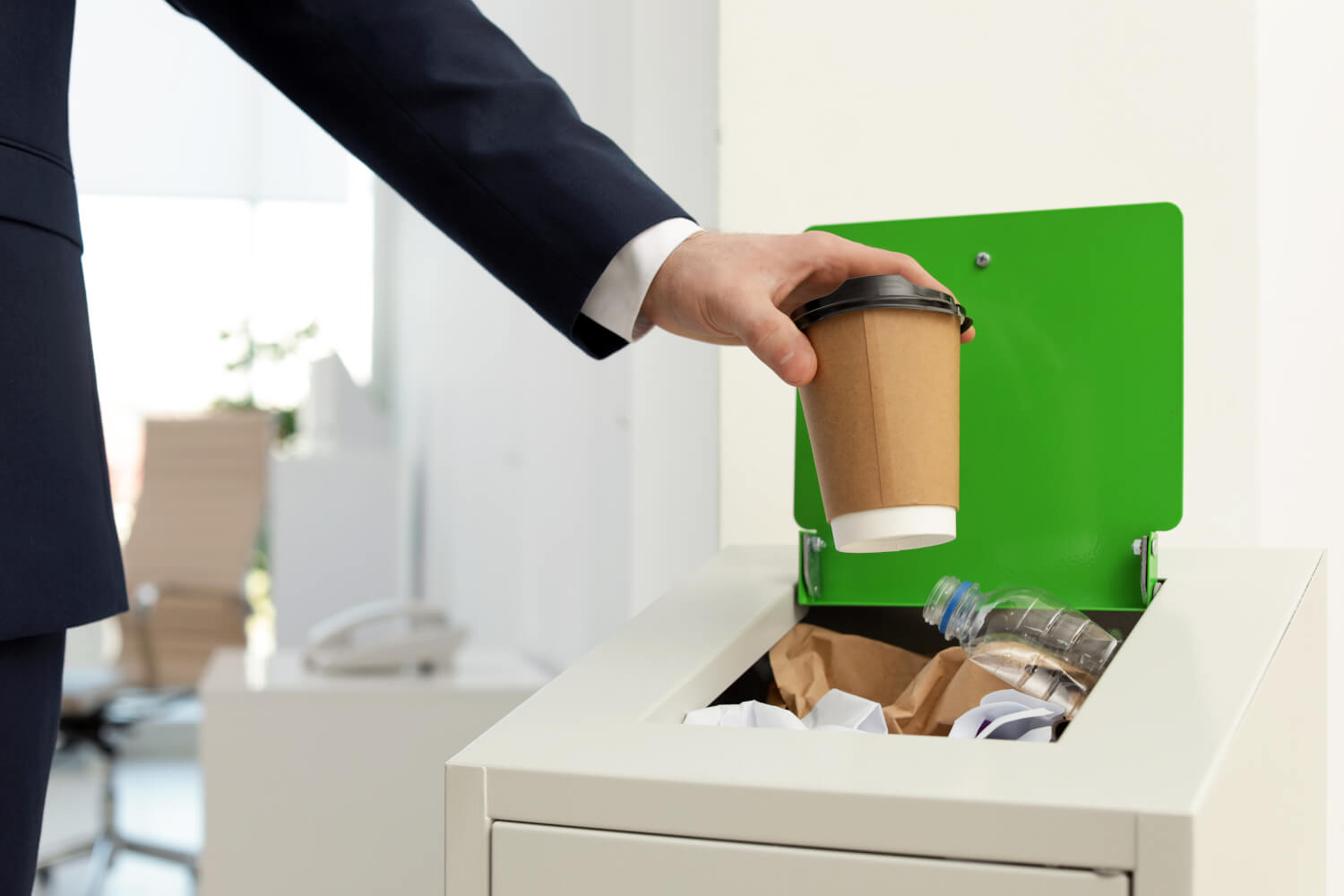 man in suit throwing away trash at office