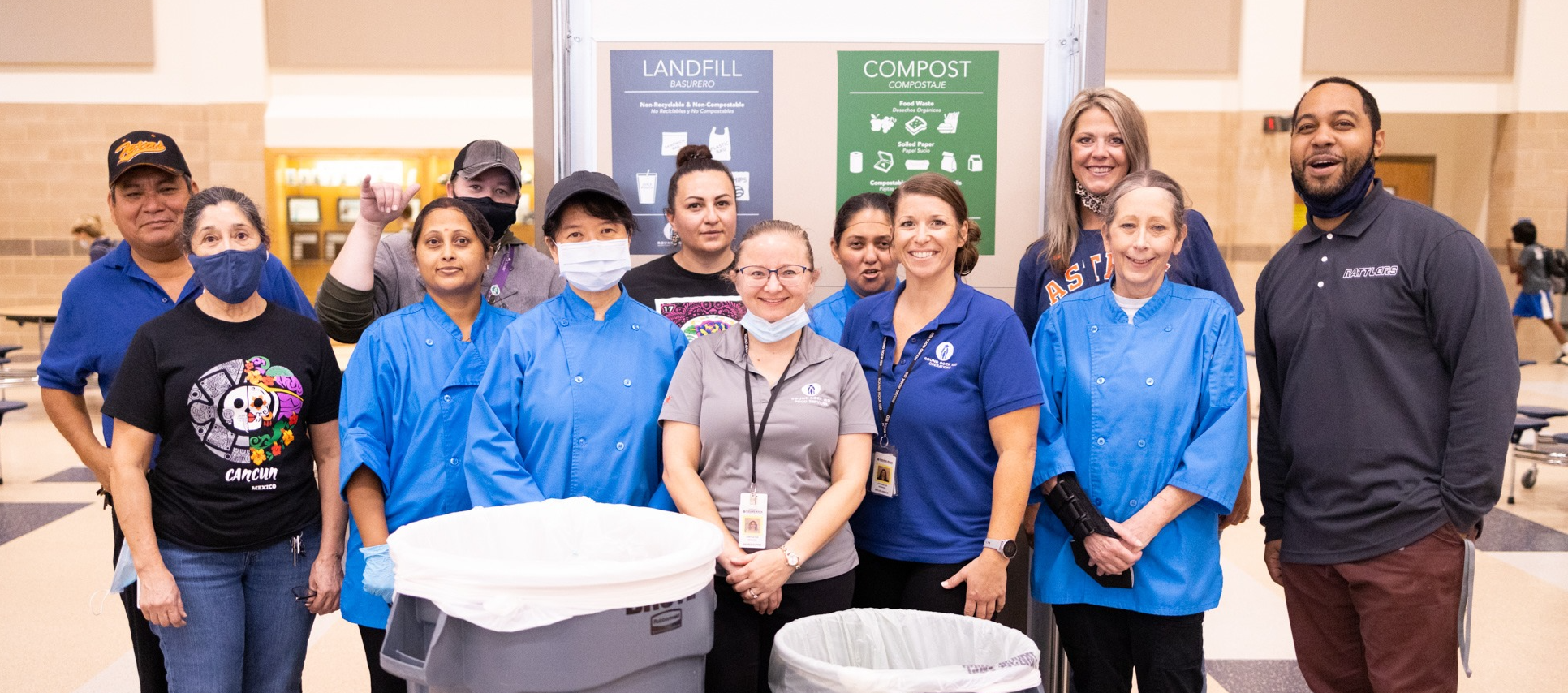 A school's staff in front of recycling compost and trash bins