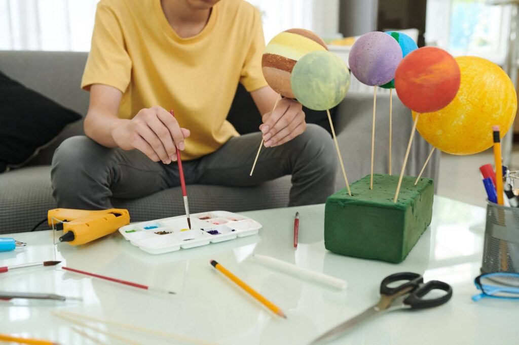 Person holding painting brushes over a table.