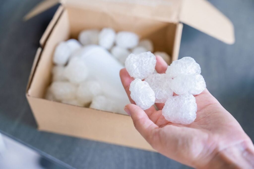 Hand holding styrofoam with a box in the background.